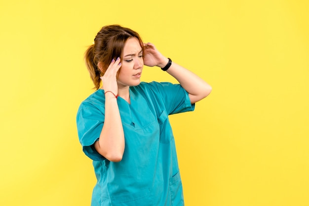 Vista frontal doctora con dolor de cabeza en el espacio amarillo