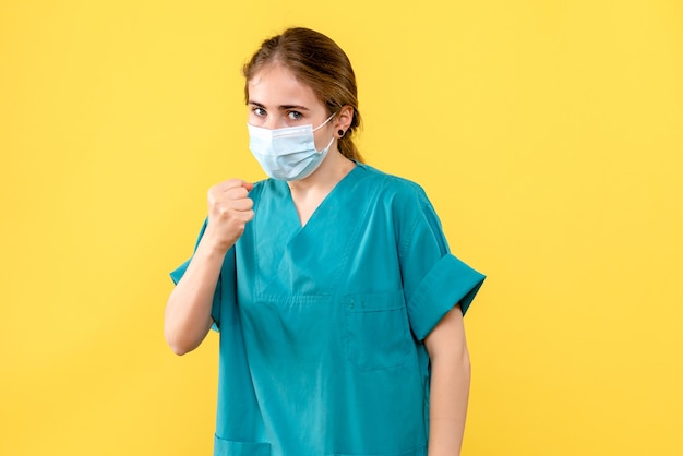 Vista frontal doctora enojada sobre fondo amarillo pandemia de covid del hospital de salud