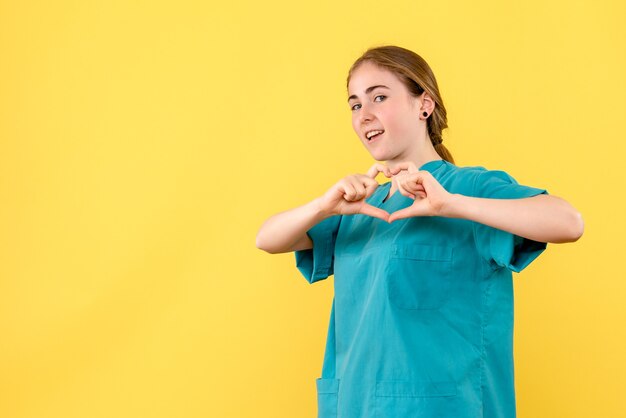 Vista frontal doctora enviando amor sobre fondo amarillo médico salud hospital virus emoción