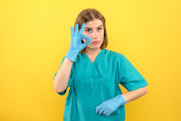 Vista frontal de la doctora con guantes azules en el hospital médico de la enfermera de piso amarillo