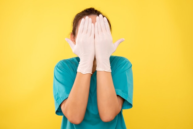 Vista frontal doctora en guantes blancos sobre fondo amarillo