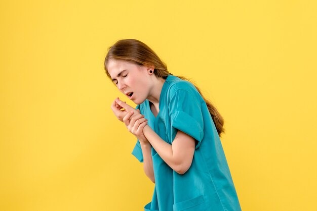 Vista frontal doctora se lastimó el brazo sobre fondo amarillo médico de salud hospital emoción