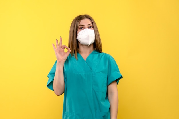 Vista frontal de la doctora con máscara en la emoción del hospital pandémico de virus de piso amarillo