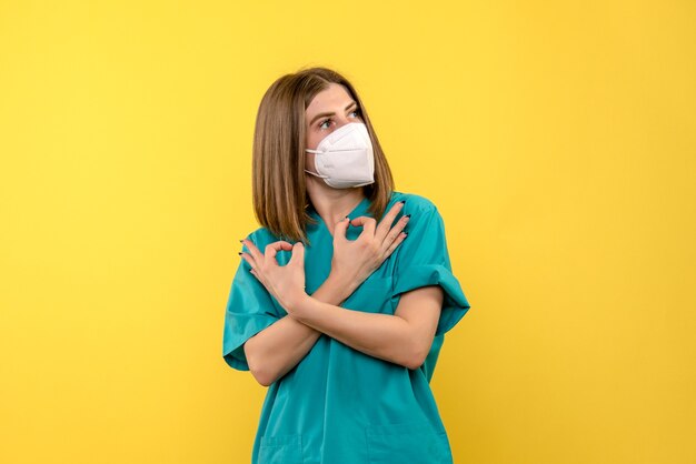 Vista frontal de la doctora con máscara en la emoción de la pandemia del hospital de virus de piso amarillo