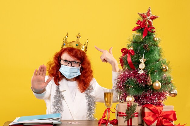 Vista frontal doctora en máscara estéril alrededor de regalos de Navidad