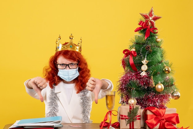 Vista frontal doctora en máscara estéril alrededor de regalos de Navidad