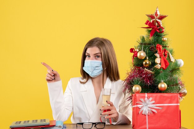 Vista frontal doctora en máscara estéril celebrando la Navidad