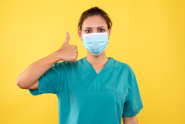 Vista frontal de la doctora en máscara estéril sobre fondo amarillo