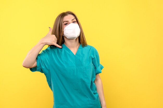 Vista frontal de la doctora con máscara en un hospital médico pandémico de piso amarillo