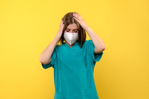 Vista frontal de la doctora con máscara en el hospital pandémico de virus de emoción de piso amarillo