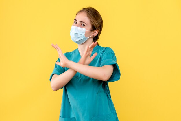 Vista frontal de la doctora en máscara en el hospital de salud de escritorio amarillo pandemia de covid