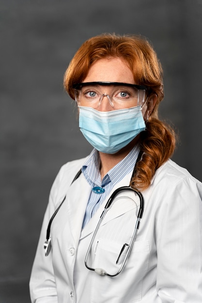 Vista frontal de la doctora con máscara médica, estetoscopio y gafas de seguridad