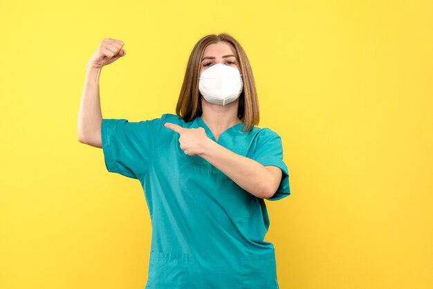 Vista frontal doctora con máscara en el piso amarillo médico del hospital pandémico