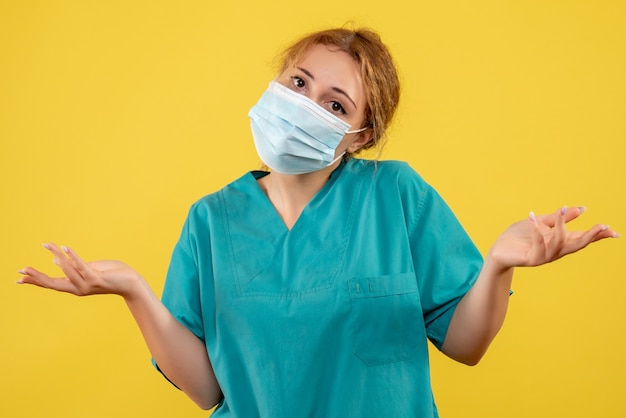 Vista frontal de la doctora en máscara protectora estéril en pared amarilla