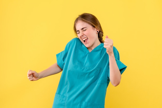 Vista frontal doctora regocijándose sobre fondo amarillo emociones médico hospital salud