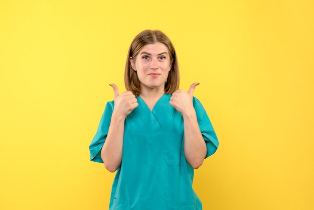 Vista frontal de la doctora con rostro sonriente en la pared amarilla