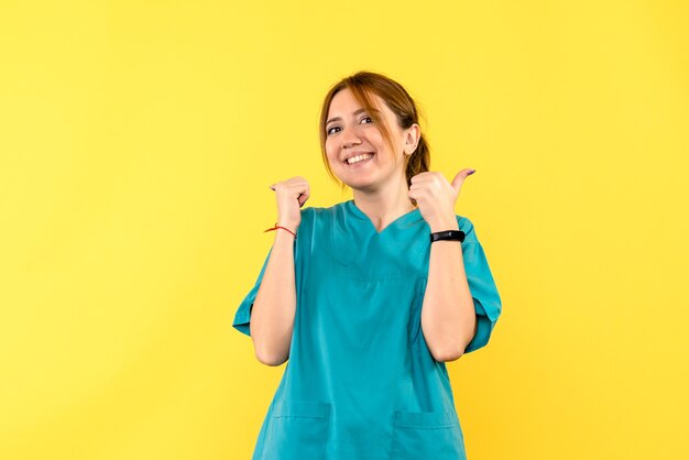 Vista frontal doctora sonriendo en espacio amarillo