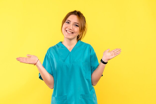 Vista frontal doctora sonriendo en espacio amarillo