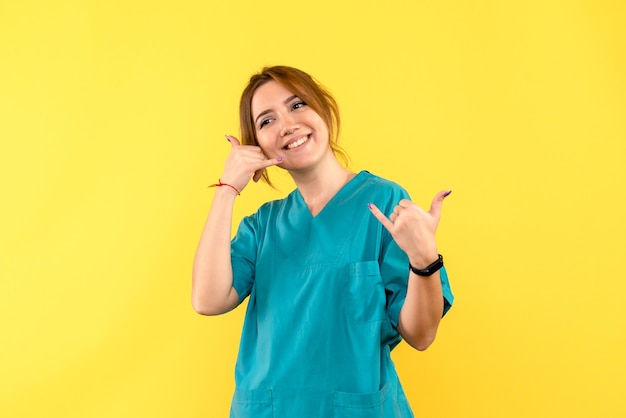 Vista frontal doctora sonriendo en espacio amarillo