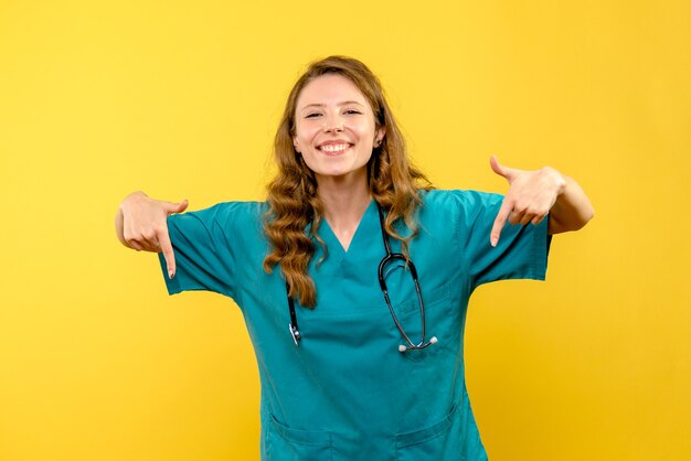 Vista frontal doctora sonriendo en espacio amarillo