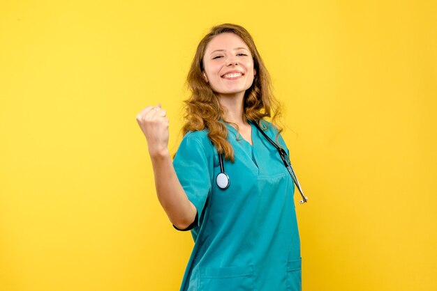 Vista frontal de la doctora sonriendo en la pared amarilla