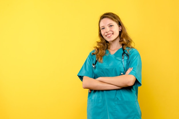 Vista frontal de la doctora sonriendo en la pared amarilla