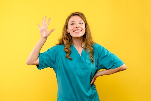 Vista frontal de la doctora sonriendo en la pared amarilla