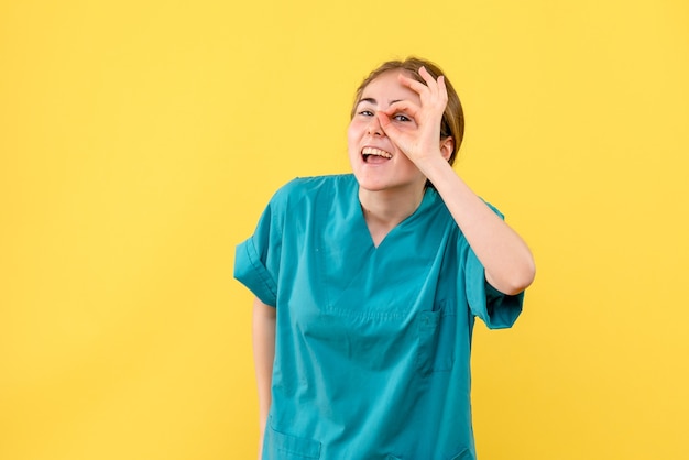 Vista frontal doctora sonriendo sobre fondo amarillo hospital médico salud emociones