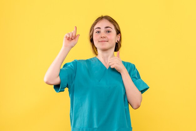 Vista frontal doctora sonriendo sobre fondo amarillo salud médico emoción hospital