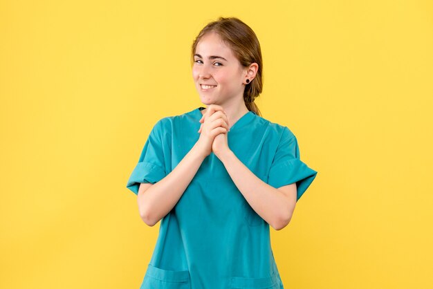 Vista frontal doctora sonriendo sobre fondo amarillo salud médico hospital emoción