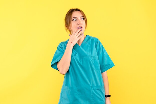 Vista frontal doctora sorprendida en espacio amarillo