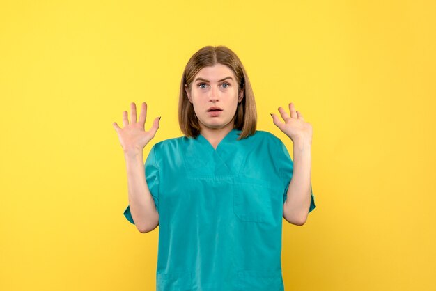 Vista frontal doctora sorprendida en espacio amarillo