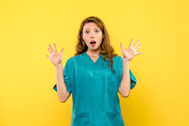 Vista frontal de la doctora sorprendida en la pared amarilla