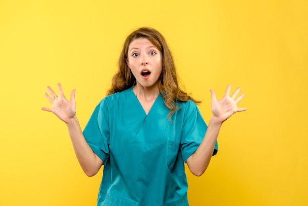 Vista frontal de la doctora sorprendida en la pared amarilla