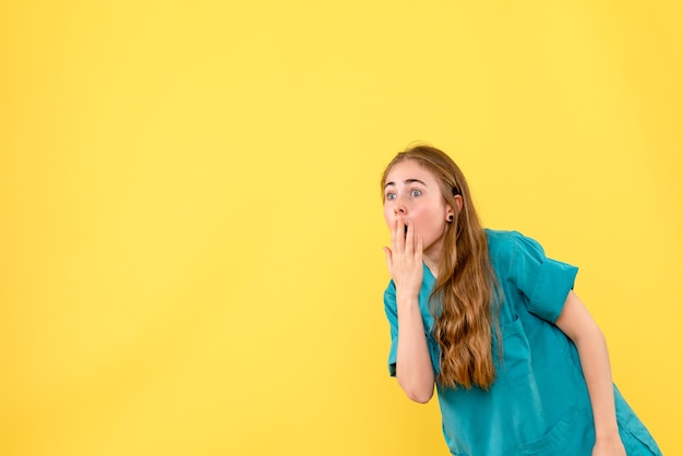 Vista frontal doctora sorprendida sobre fondo amarillo salud médico emoción virus hospital