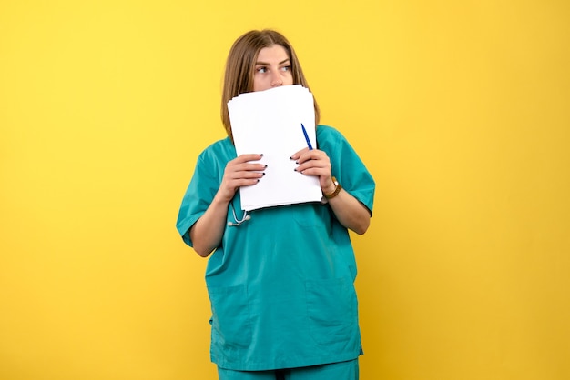 Vista frontal doctora sosteniendo documentos en espacio amarillo