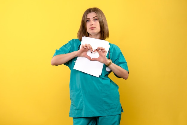 Foto gratuita vista frontal doctora sosteniendo documentos en espacio amarillo