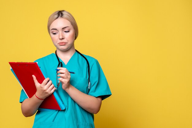 Vista frontal doctora sosteniendo notas y papeles, ambulancia covid-19 enfermera hospital de salud