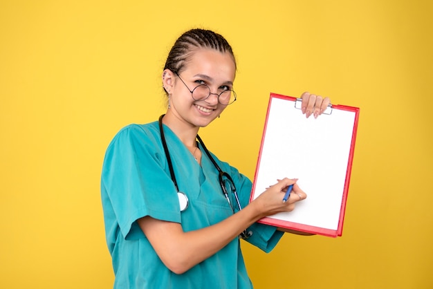 Foto gratuita vista frontal doctora sosteniendo portapapeles médico, color enfermera hospital emoción covid-19 salud