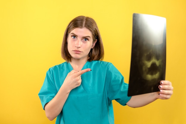 Foto gratuita vista frontal doctora sosteniendo radiografía en espacio amarillo