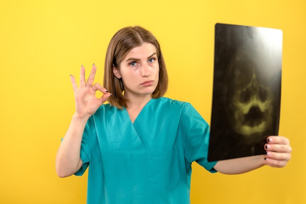 Vista frontal doctora sosteniendo radiografía en espacio amarillo