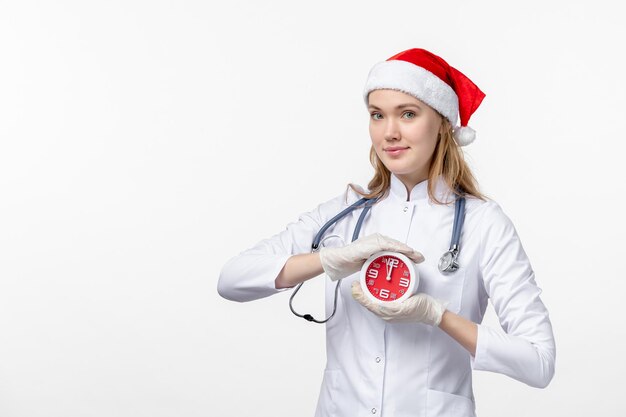 Foto gratuita vista frontal de la doctora sosteniendo el reloj en la pared blanca