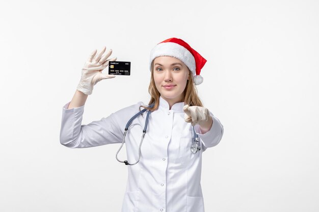 Vista frontal de la doctora sosteniendo una tarjeta bancaria en la pared blanca