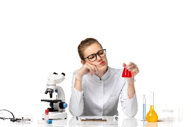 Vista frontal doctora en traje médico blanco con guantes sosteniendo matraz con solución en espacio en blanco