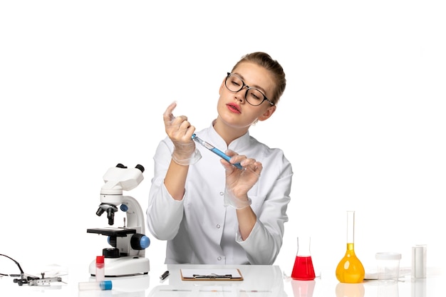 Vista frontal doctora en traje médico blanco con guantes trabajando con soluciones en espacios en blanco