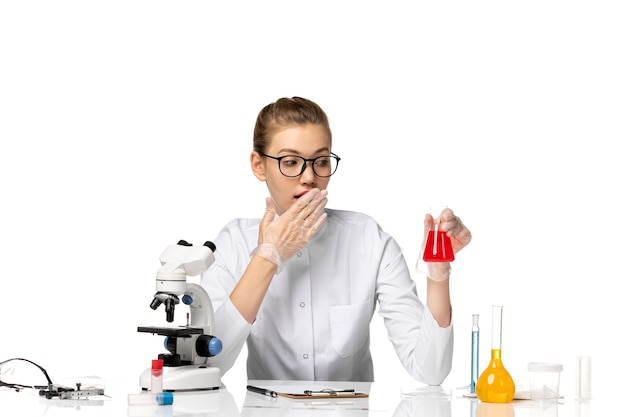 Foto gratuita vista frontal de la doctora en traje médico con guantes que sostienen la solución en el espacio en blanco