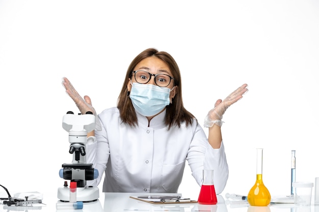 Vista frontal doctora en traje médico con máscara debido a covid posando en un espacio en blanco