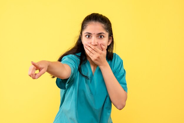 Foto gratuita vista frontal doctora en uniforme apuntando a algo