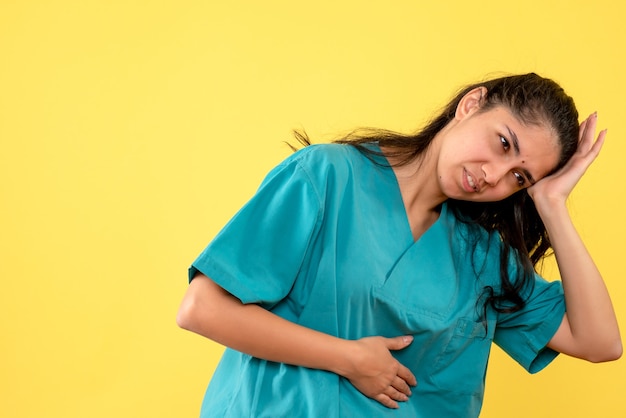 Vista frontal doctora en uniforme sosteniendo su cabeza de pie