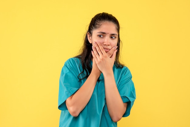 Foto gratuita vista frontal doctora en uniforme sosteniendo su rostro de pie